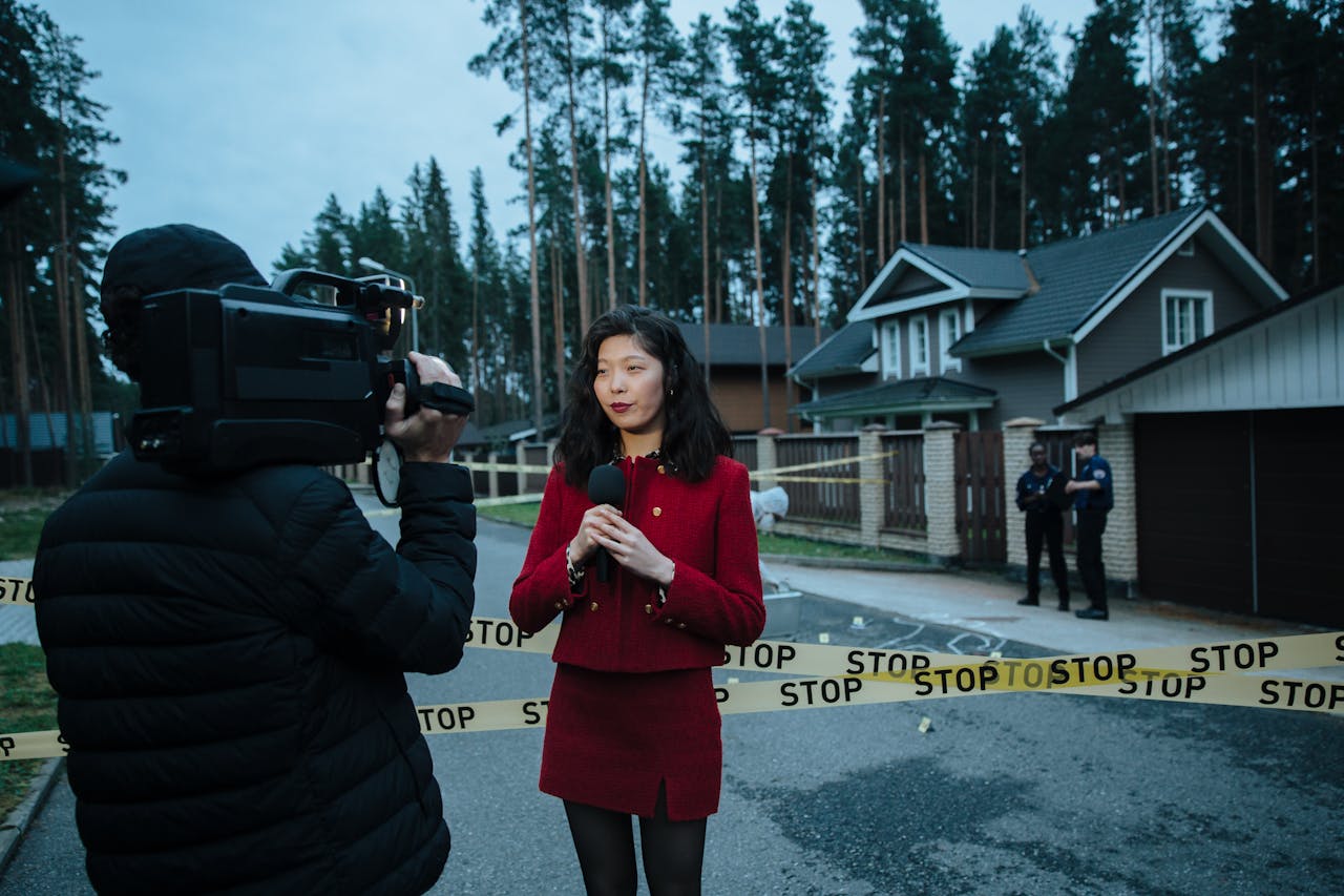 heros-img Journalist reporting live from a taped crime scene with cameraman and police.
